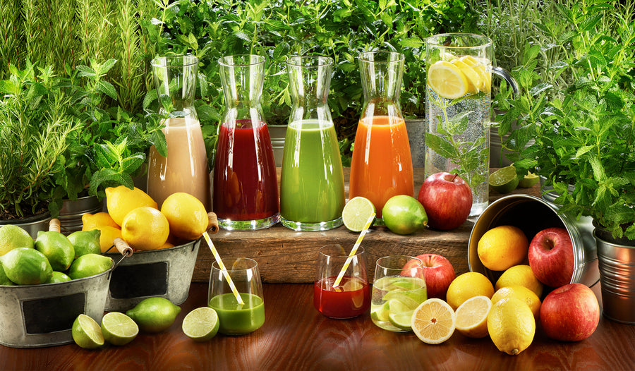 Jarras de zumos naturales de colores con limones, limas, manzanas y hierbas aromáticas para un coffee break