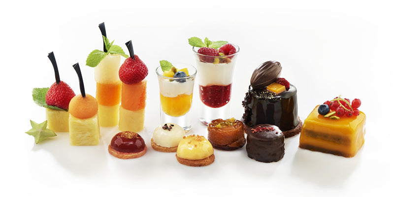 Selección de mini postres con brochetas de fruta, vasitos de yogur con frutos rojos y pastelitos de chocolate