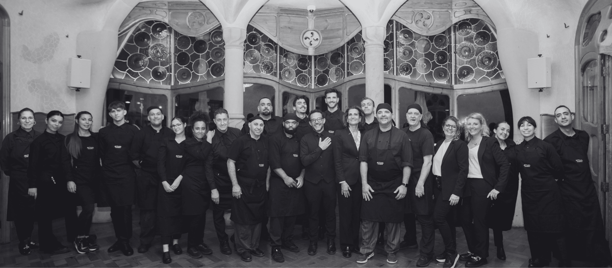 Equipo de cocina y sala de Actual Catering, con uniformes negros, reunido en un edificio modernista de Barcelona