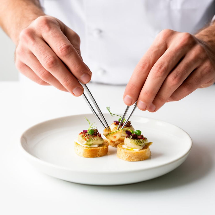 Chef emplatando con pinzas unos canapés de pan con crema y micro brotes en el obrador de Barcelona